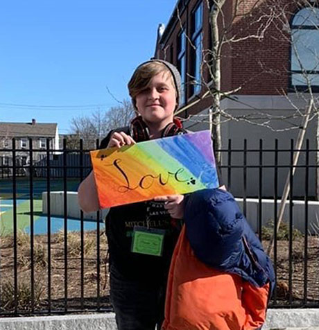 James holding a sign that says "love."