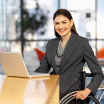 A woman in a wheelchair works on a laptop