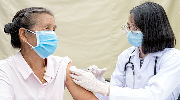 A doctor vaccinates an elderly patient to prevent the spread of the virus.