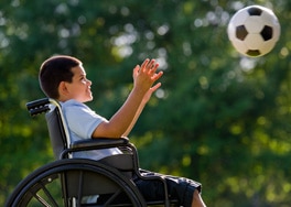 Photo of a boy in wheelchair tossing soccer ball