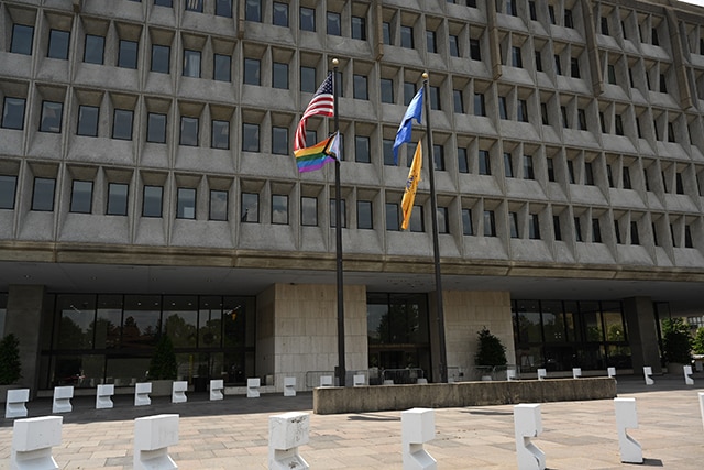 Progress Pride flag, American flag, HHS flag and Public Health Service flag waving in the wind outside of Hubert H. Humphrey Building on June 1, 2022.