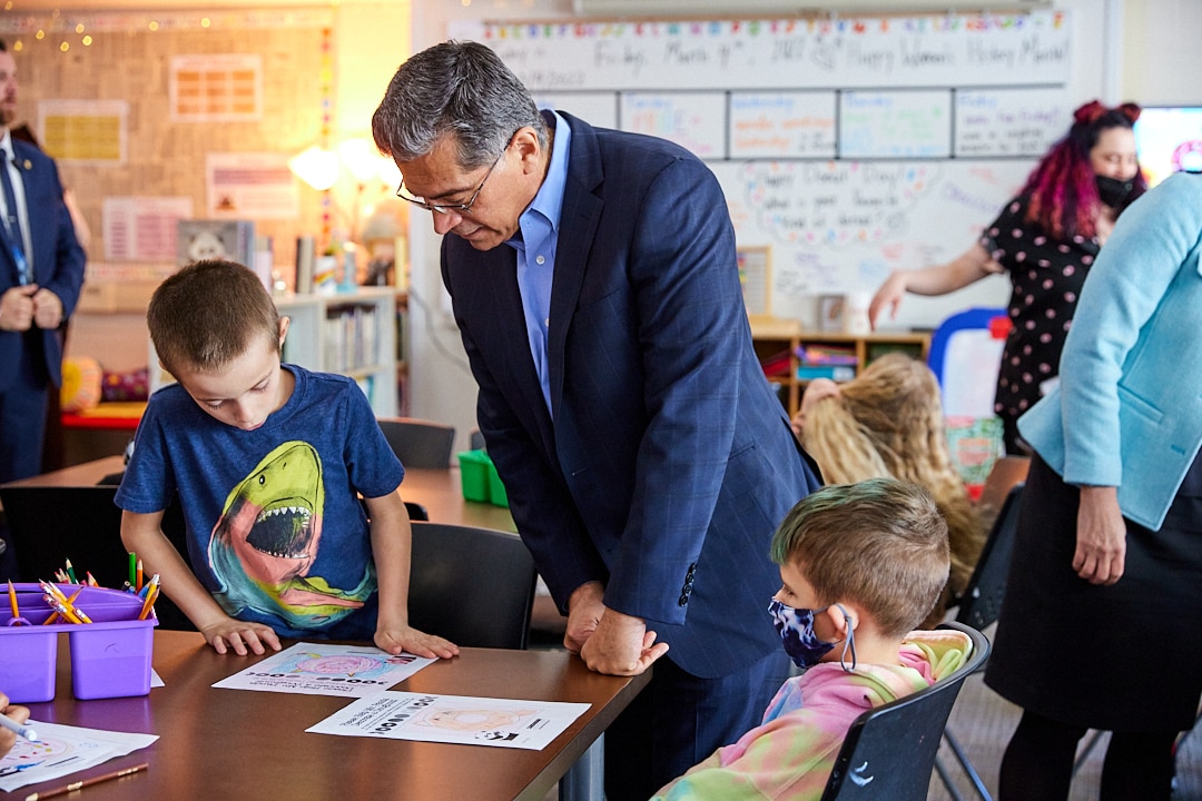 HHS Secretary Becerra interacting with two children at a table the Boys and Girls Club of Manchester. 