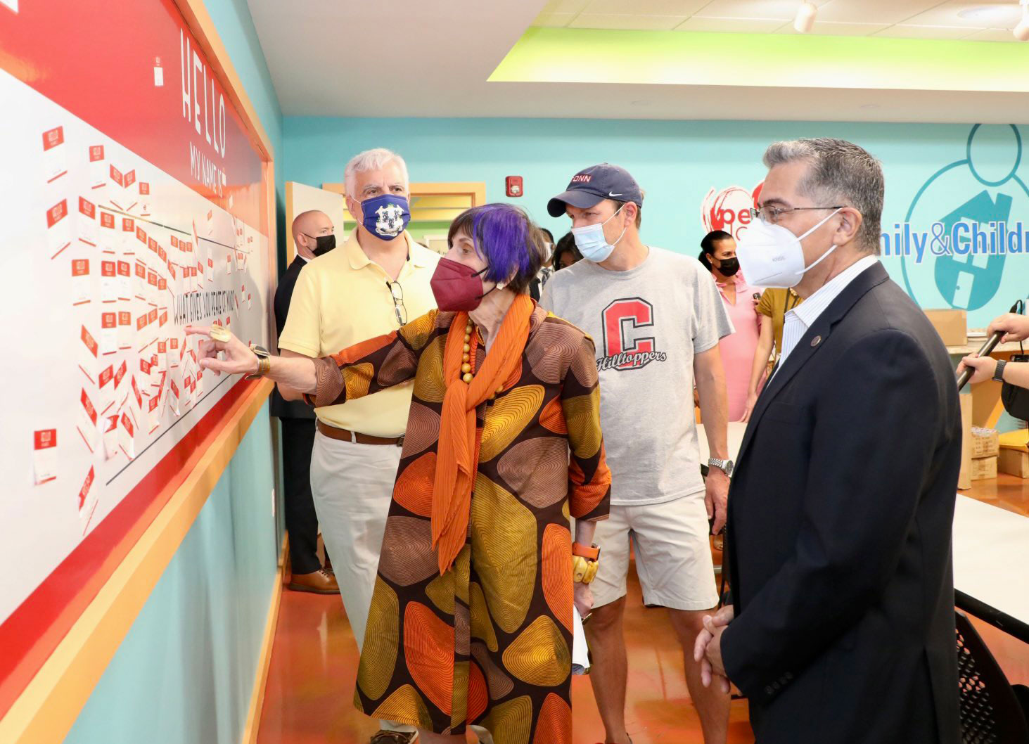 Secretary Becerra in front of whiteboard with others and children’s center.