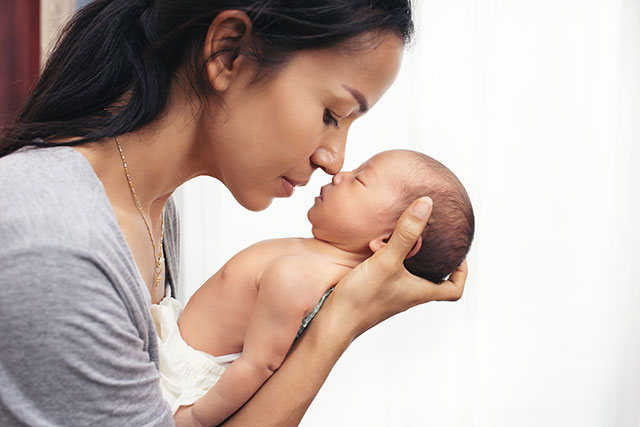 A mother touching noses with her newborn