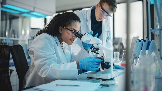 Lab techs looking into microscope