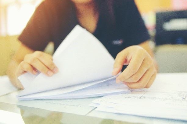 Woman thumbing through stack of papers