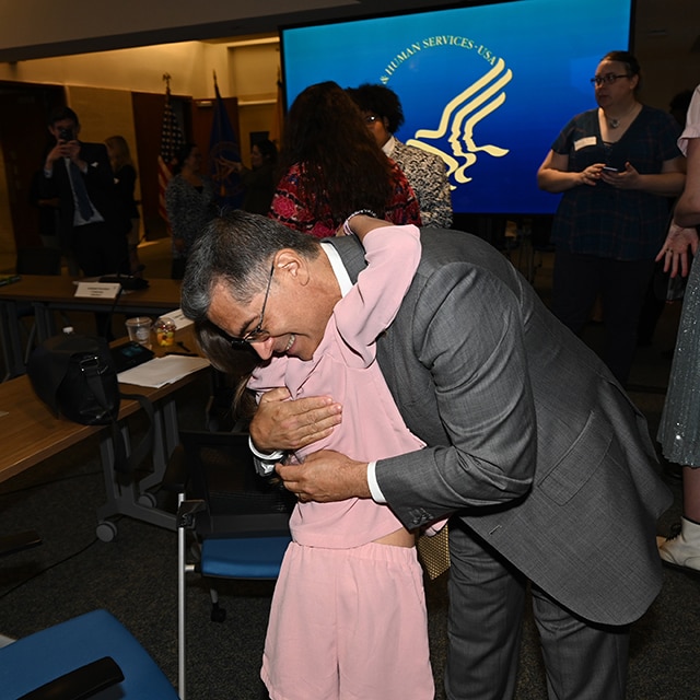 Secretary Becerra and a child embracing in a hug after the youth trans roundtable event