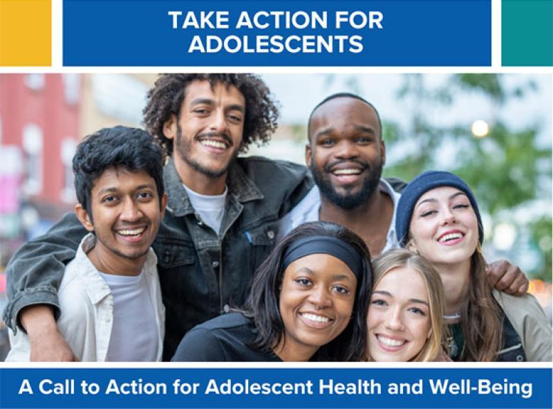 A group of women and men smiling taking a group photo outside.