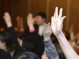 Photo of hands being raised at a meeting