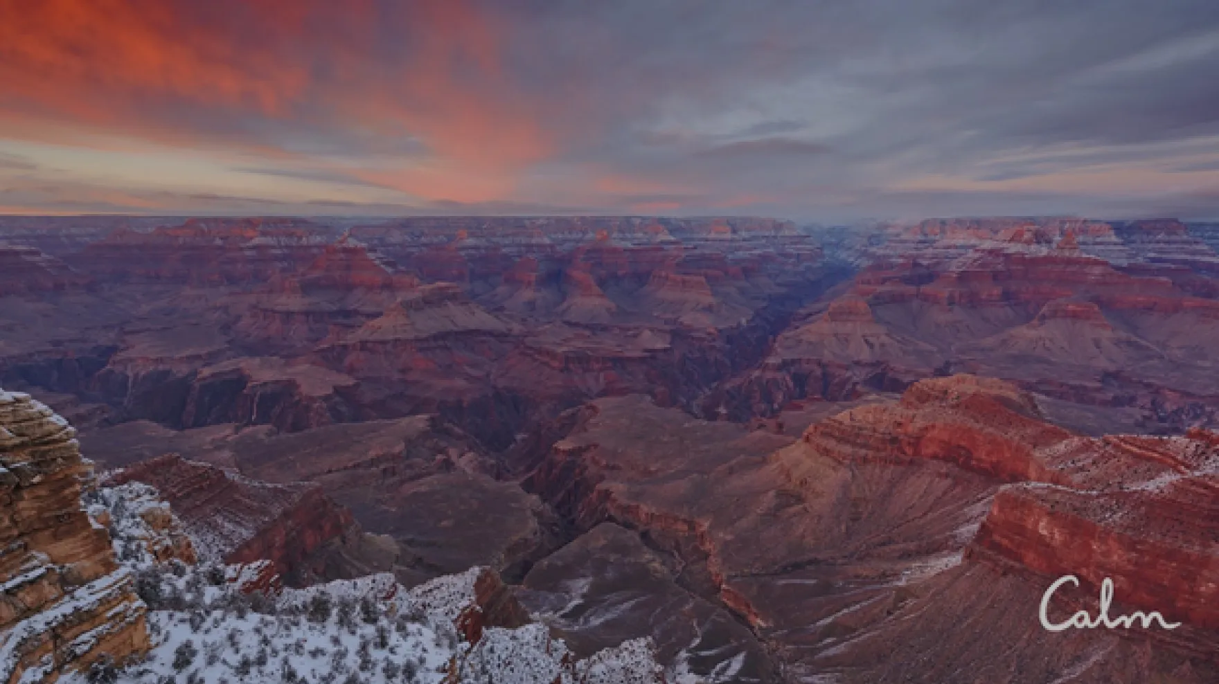 The Grand Canyon at sunset, with a light dusting of snow on the ground. The Calm logo is in the lower right corner.